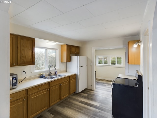 kitchen featuring dark wood-type flooring, stove, white refrigerator, and sink