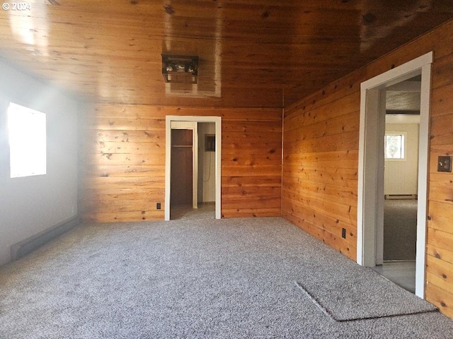 unfurnished room featuring carpet flooring, wooden walls, and wood ceiling