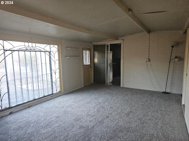 carpeted empty room featuring beam ceiling