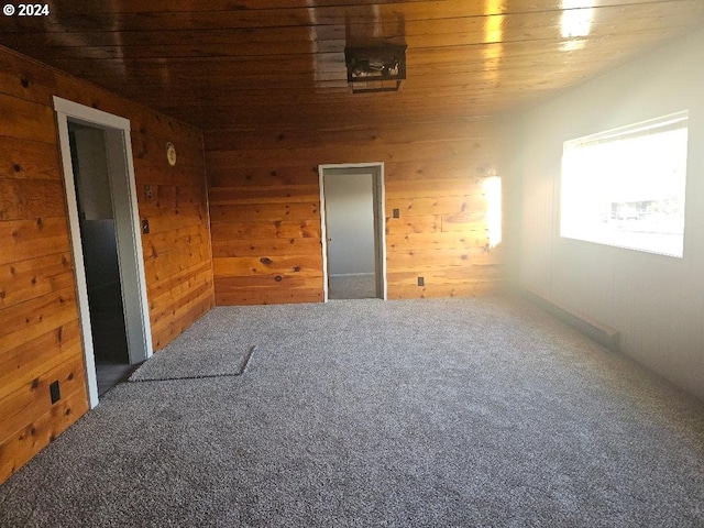 carpeted spare room featuring wood walls and wood ceiling