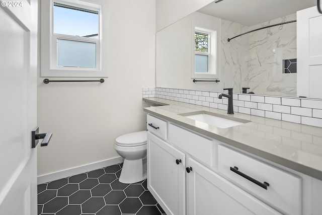 bathroom with tasteful backsplash, vanity, tiled shower, tile patterned flooring, and toilet