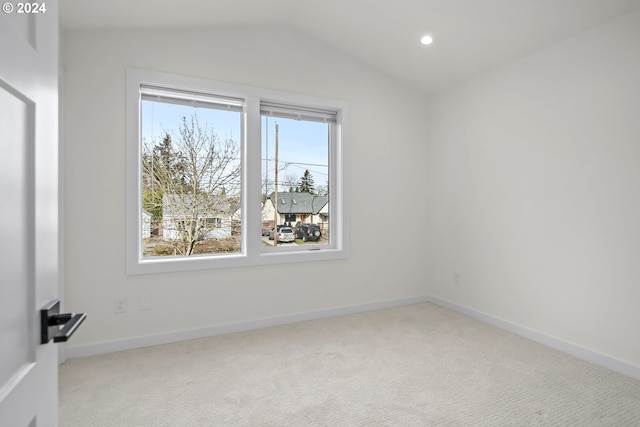 empty room with a healthy amount of sunlight, light colored carpet, and vaulted ceiling