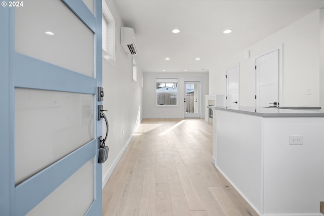 corridor featuring light hardwood / wood-style flooring and an AC wall unit