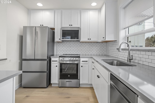 kitchen with white cabinets, stainless steel appliances, light hardwood / wood-style floors, and sink