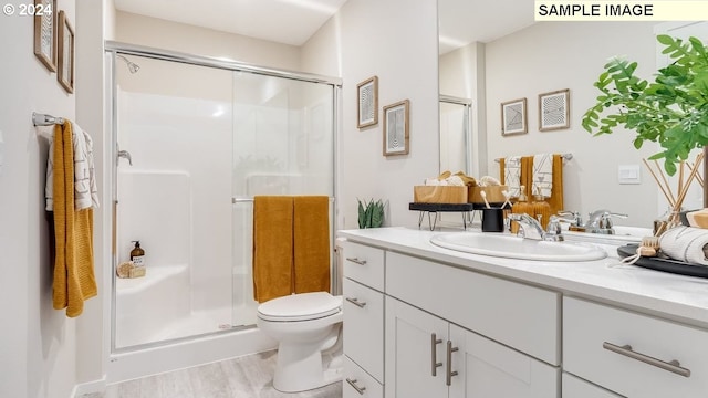 bathroom featuring wood-type flooring, vanity, a shower with shower door, and toilet