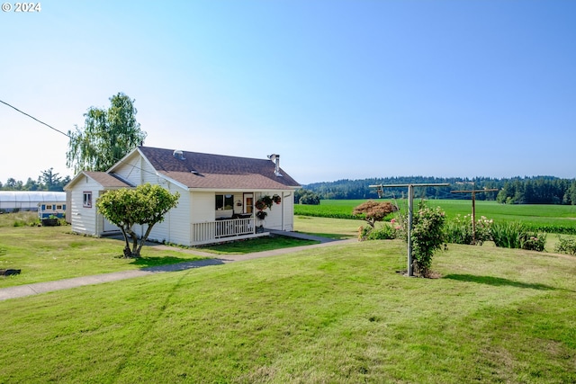 back of house featuring covered porch, a rural view, and a yard