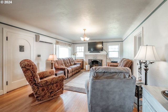 living room with a fireplace, an inviting chandelier, light hardwood / wood-style floors, and a wall mounted air conditioner