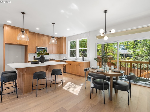 kitchen featuring decorative backsplash, pendant lighting, a center island, and light hardwood / wood-style flooring