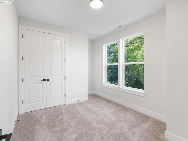 unfurnished bedroom featuring light colored carpet and a closet