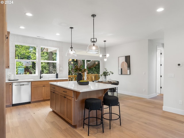 kitchen featuring a center island, light hardwood / wood-style flooring, decorative light fixtures, stainless steel dishwasher, and sink