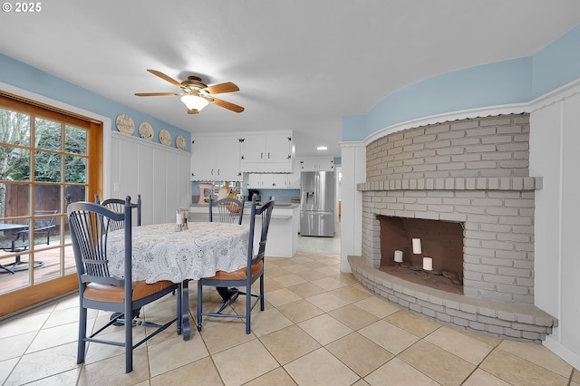 tiled dining space with ceiling fan and a fireplace