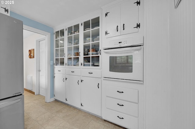 kitchen featuring white cabinets, stainless steel fridge, and oven