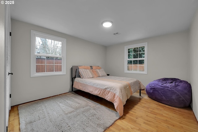 bedroom with multiple windows and light hardwood / wood-style floors