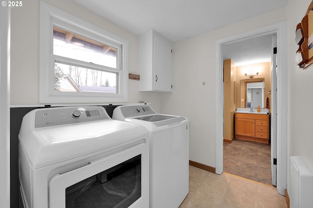 laundry area featuring radiator heating unit, cabinets, and washing machine and clothes dryer