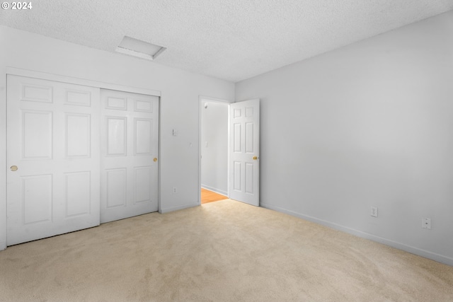 unfurnished bedroom with a closet, a textured ceiling, and light colored carpet