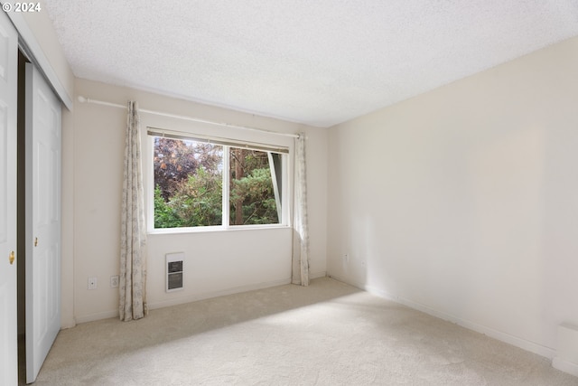 carpeted empty room with a textured ceiling and heating unit