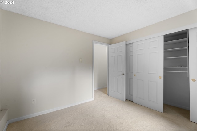 unfurnished bedroom featuring a closet, light carpet, and a textured ceiling