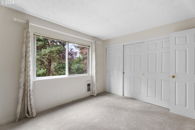 unfurnished bedroom featuring light carpet, a textured ceiling, and a closet