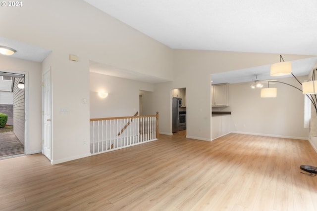 unfurnished living room featuring vaulted ceiling, light wood-type flooring, and plenty of natural light