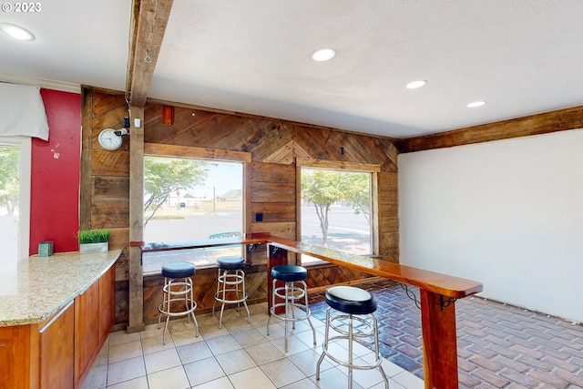 unfurnished dining area featuring wood walls, plenty of natural light, and beamed ceiling