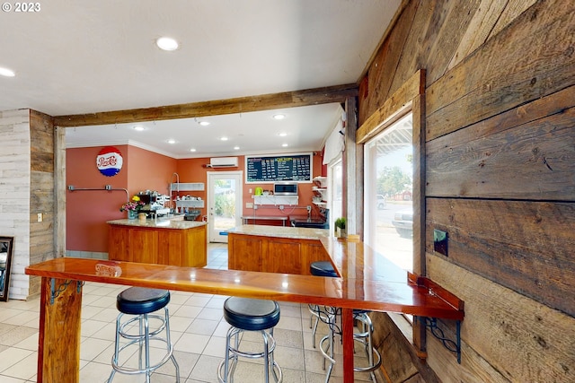 kitchen with a kitchen island, kitchen peninsula, wooden walls, and light tile floors