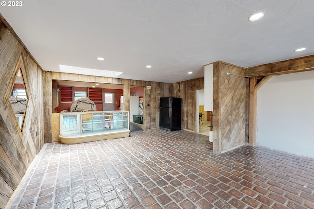 unfurnished living room featuring wood walls