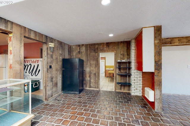 kitchen with wooden walls, white refrigerator, and black fridge