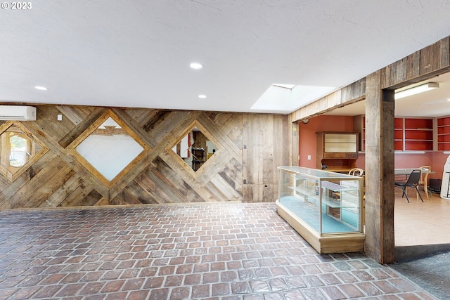 interior space with a skylight, wood walls, and a wall unit AC