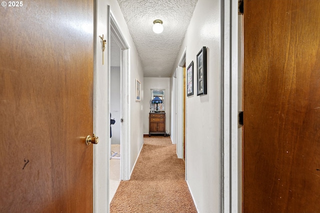 hall featuring a textured ceiling and light carpet