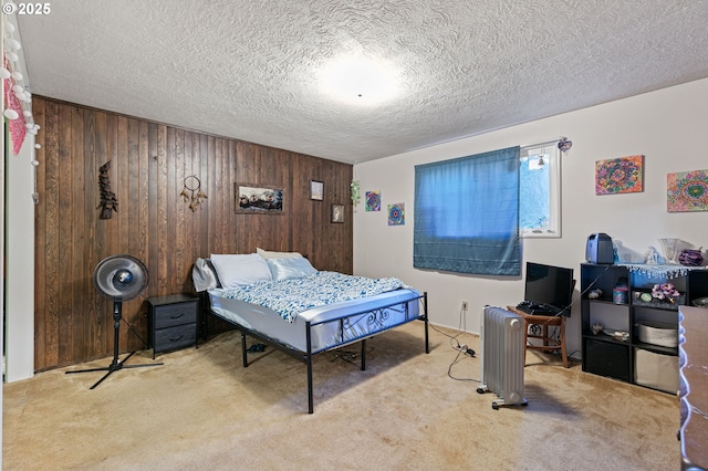 bedroom featuring a textured ceiling, light colored carpet, and wood walls