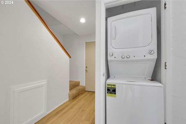 washroom with light hardwood / wood-style floors and stacked washer / dryer