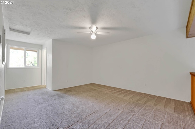 unfurnished room featuring light colored carpet, ceiling fan, and a textured ceiling