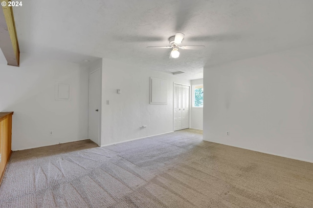 unfurnished room with light colored carpet, ceiling fan, and a textured ceiling