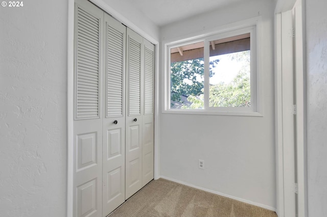 unfurnished bedroom with light colored carpet and a closet