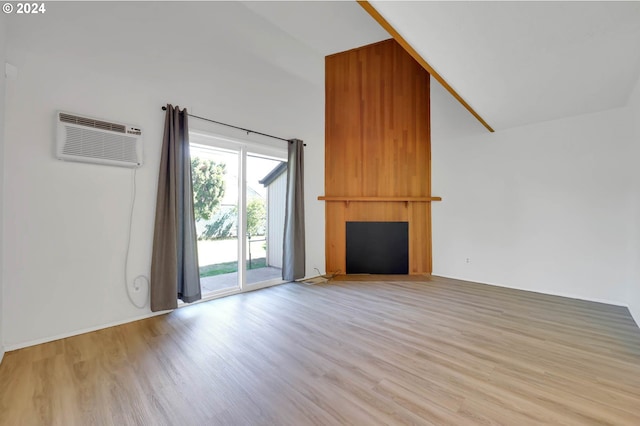 unfurnished living room featuring lofted ceiling, a large fireplace, light hardwood / wood-style flooring, and a wall mounted AC