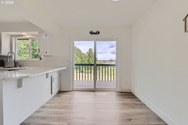 kitchen with a sink, visible vents, white cabinets, light countertops, and light wood-type flooring