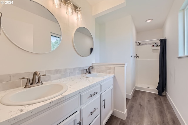 full bath featuring double vanity, wood finished floors, a stall shower, and a sink