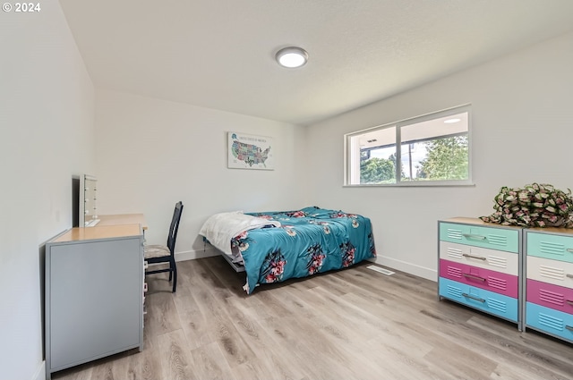 bedroom with light wood-type flooring and baseboards