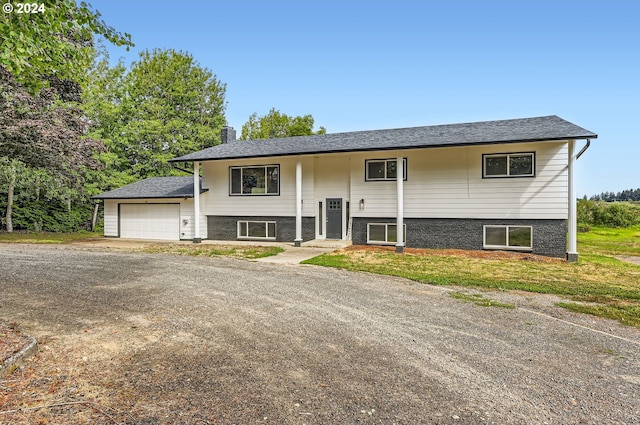 bi-level home with dirt driveway, a chimney, and an attached garage