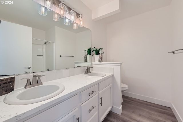 full bath with toilet, double vanity, baseboards, and a sink