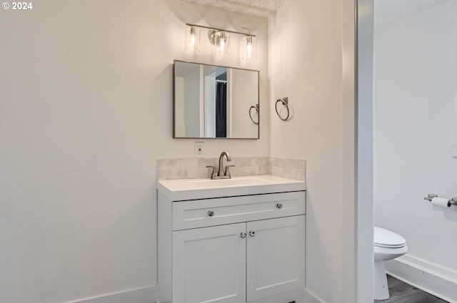 bathroom featuring wood finished floors, vanity, toilet, and baseboards