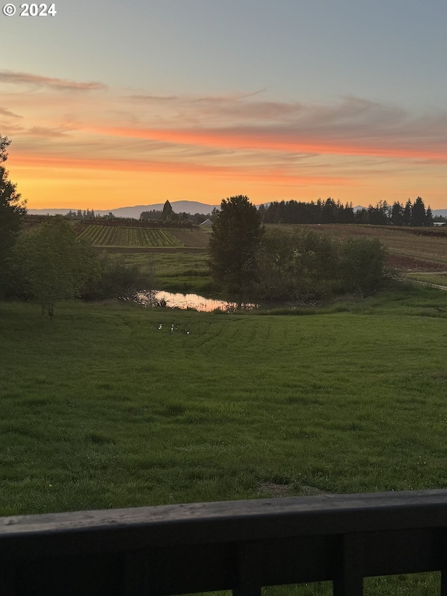 yard at dusk featuring a rural view