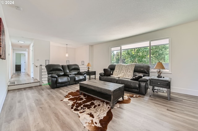 living area with light wood-type flooring, baseboards, and a textured ceiling