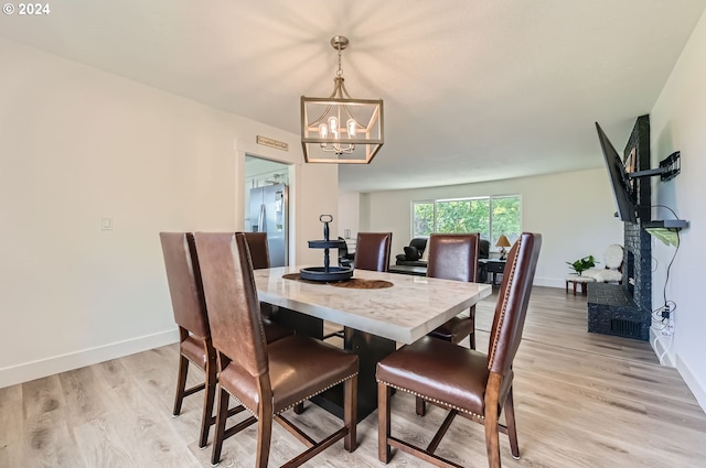 dining area with a chandelier, baseboards, and light wood-style floors