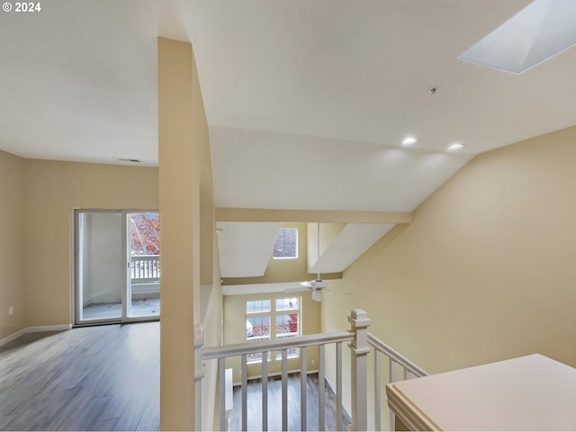 stairway featuring hardwood / wood-style floors, ceiling fan, and vaulted ceiling with skylight