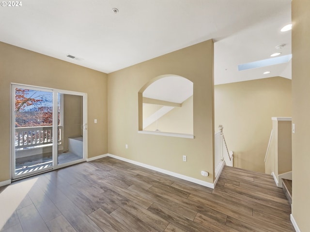 empty room with a skylight and hardwood / wood-style flooring