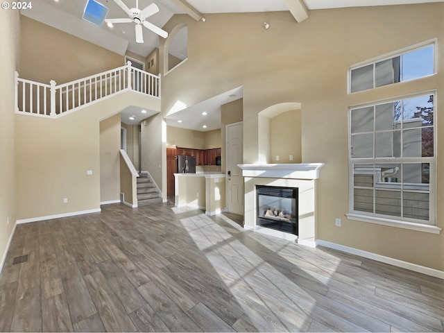 6357 NE Brighton St, Hillsboro, OR 97124 - unfurnished living room with ceiling fan, wood finished floors, beam ceiling, high vaulted ceiling, and baseboards