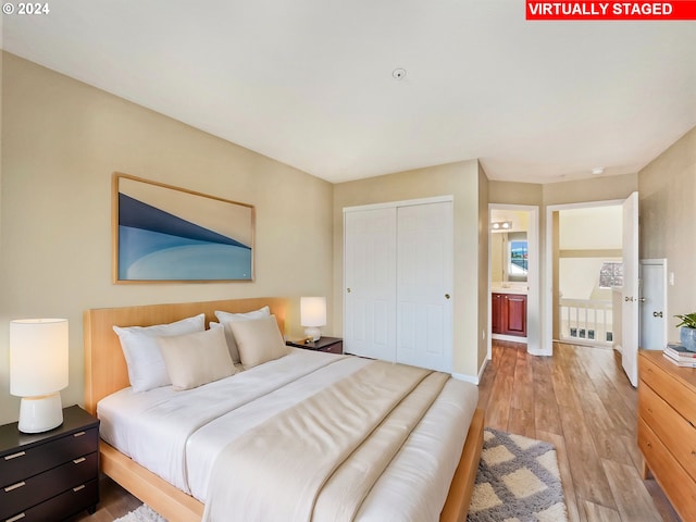 bedroom featuring ensuite bath, a closet, and light hardwood / wood-style floors