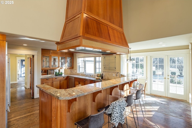 kitchen with decorative light fixtures, dishwasher, sink, a high ceiling, and custom range hood