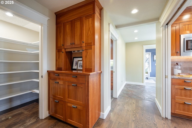 interior space featuring dark hardwood / wood-style floors, stainless steel microwave, and decorative backsplash